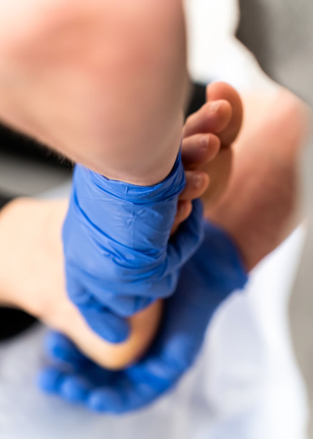 Hands in blue gloves manipulating a foot