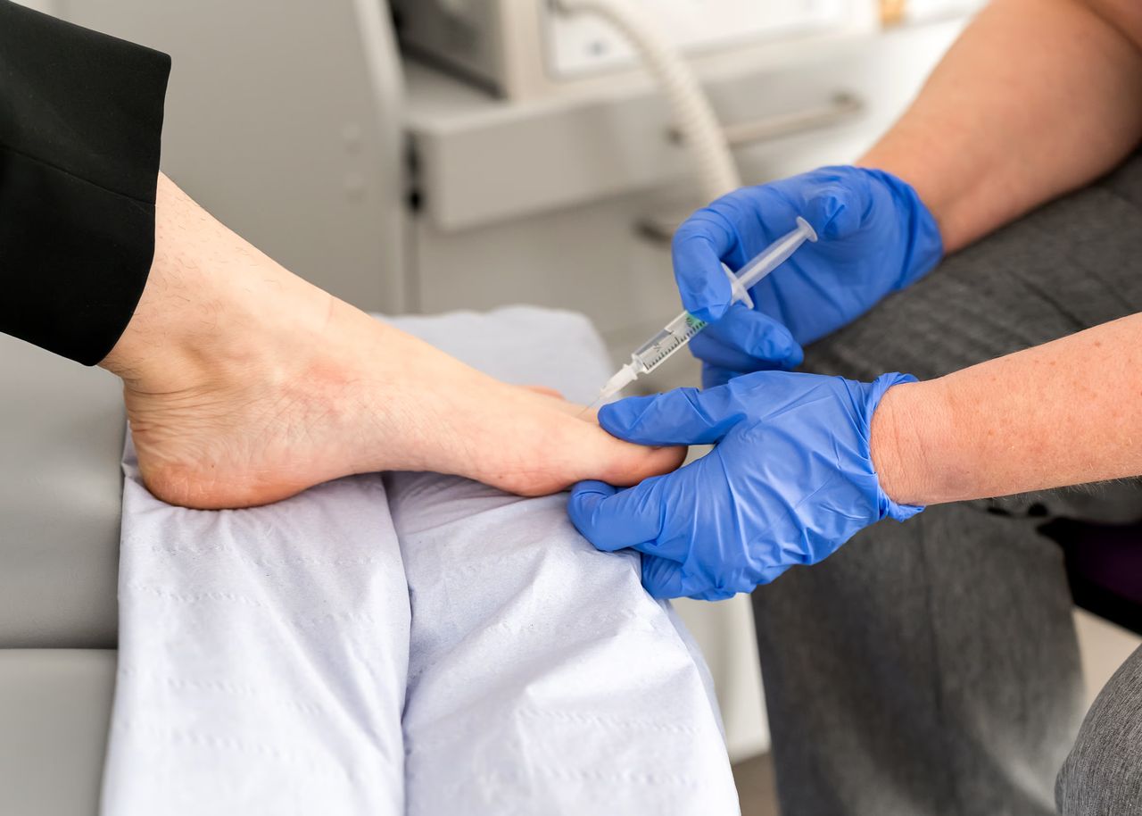 A Chase Podiatry podiatrist is injecting a patients first toe